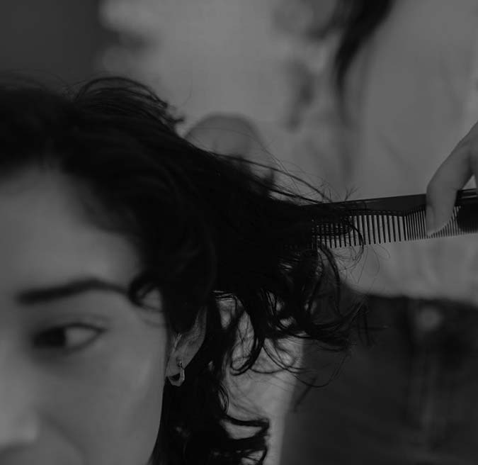 A woman receives a haircut from another woman in a bright salon setting.